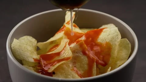 Squeezing a lemon with a juicer on circular  potato chips slowmotion Stock Footage 280089889