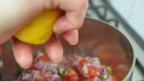 Squeezing a lemon over a cooking salsa in a pan on the gas stove in 4k. Stock Footage 142682746