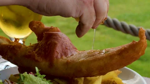 Squeezing Lemon Over Fish and Chips Outdoors With Beer Vídeos de archivo 320670999