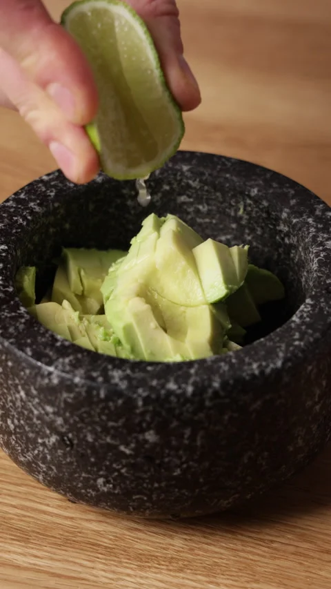 Squeezing Lime Juice over Avocado Vertical Front View Vidéo 336580066