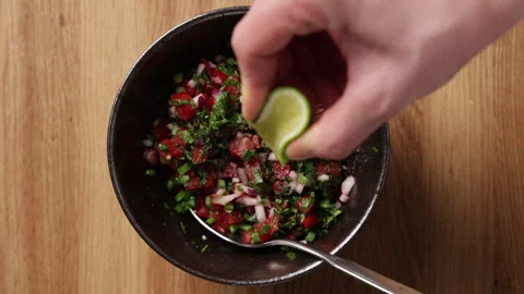 Squeezing Lime Juice over Fresh Tomato Salsa Top View Видео 336575011