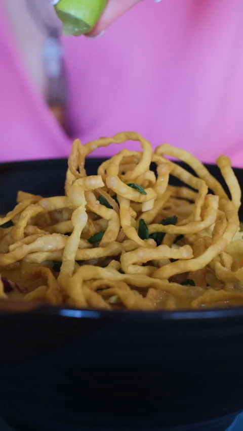 Squeezing lime onto Khao Soi noodle dish Stockbeeldmateriaal 344658342