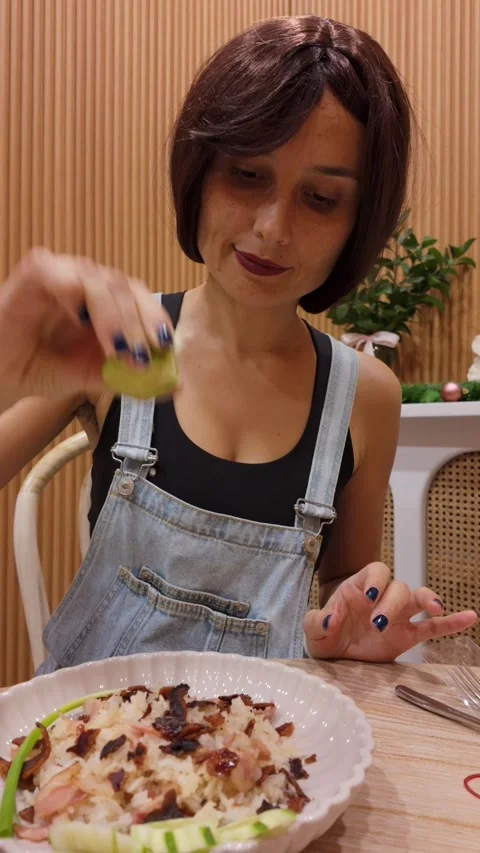 Squeezing lime over fresh salad indoors Stock Footage 312635443