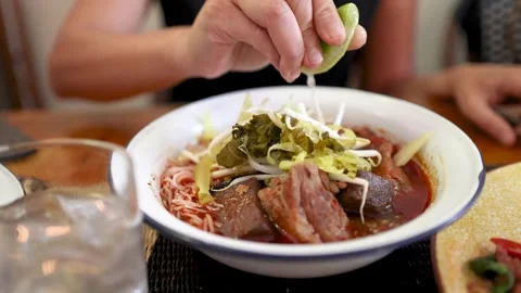 Squeezing Lime Over Northern Thai Curry Noodle Soup Stock Footage 314409167