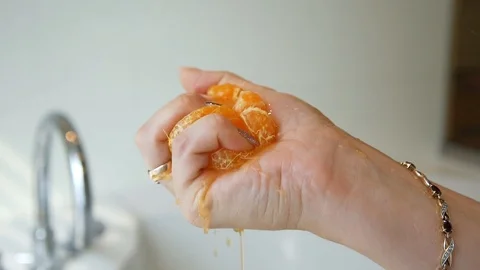 Squeezing mandarin in female hand, slow motion. Stock Footage 121588058