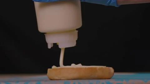 Squeezing mayonnaise on a bun with chef's hands 库存影片 221184934