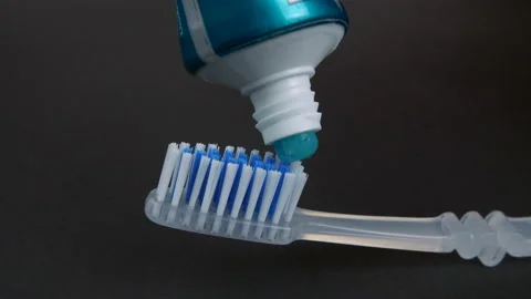 Squeezing or spreading or applying of blue toothpaste on a grey toothbrush Stock Footage 157084167