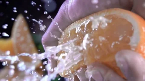 Squeezing an orange half on black background. Citrus fruit source of vitami.. Stock Footage 265841124