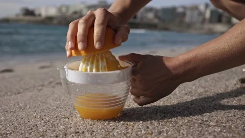 Squeezing orange juice on the ocean shore Stock Footage 209576413
