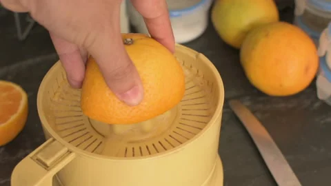 Squeezing oranges with electric juicer in the kitchen Stock Footage