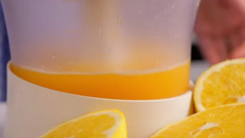Squeezing oranges tangerines juice using electric juicer in kitchen at home. Stock Footage 312985766