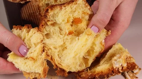 Squeezing a piece of fresh Panettone in hands, showing airy, fluffy texture and Stock Footage 306157014