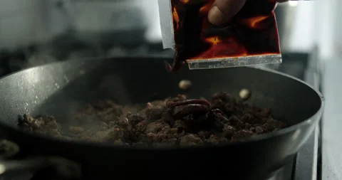 Squeezing Sauce Packet On Hamburger Meat In Skillet - 4k Stock Footage 169968043