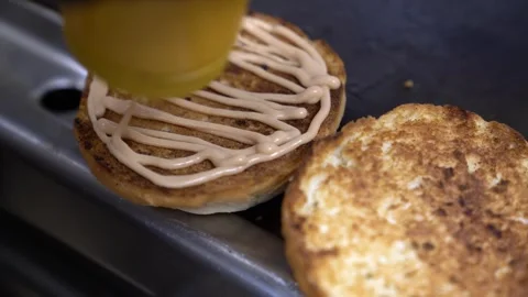 Squeezing sauce on toasted burger buns in a professional kitchen Stock Footage 338013159