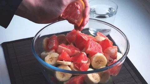 Squeezing slice of grapefruit on top of fruit salad in slow motion Stock Footage 86682941