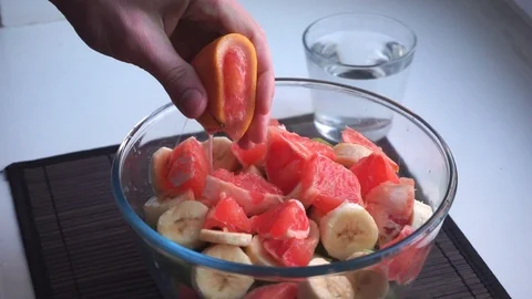 Squeezing slice of grapefruit on top of fruit salad in slow motion Stock Footage 86682966