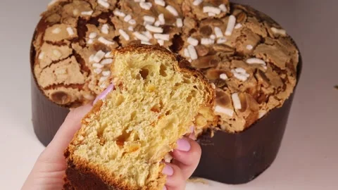 Squeezing a slice of traditional Italian Easter Colomba cake in hand, showing Stock Footage 306152327