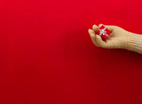 Squeezing a small red box with a Christmas present in her palm, a woman's hand Stock Photos