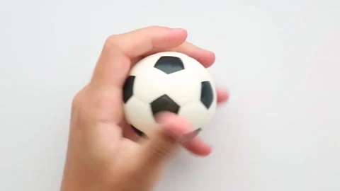 Squeezing a soccer-shaped stress ball in hand Stock Footage 314532986