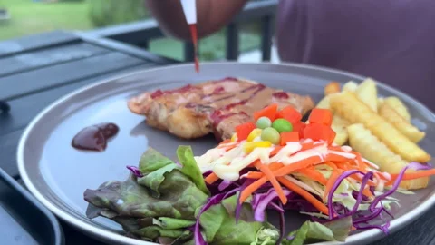 Squeezing tomato ketchup from a bottle onto a grilled chicken steak plate. Stock Footage 341953926