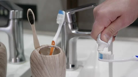Squeezing toothpaste onto a toothbrush in the bathroom Stock Footage 212620287