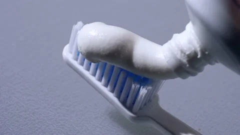 Squeezing toothpaste onto toothbrush Stock Footage 217781539