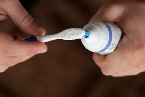 Squeezing toothpaste onto a toothbrush, male hands. Personal hygiene. Black b Stock Photos