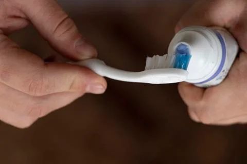 Squeezing toothpaste onto a toothbrush, male hands. Personal hygiene. Black b Stock Photos