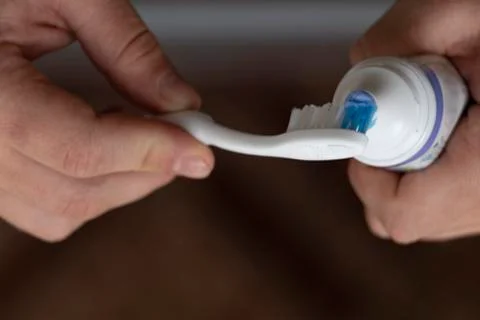 Squeezing toothpaste onto a toothbrush, male hands. Personal hygiene. Black b Stock Photos