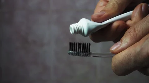 Squeezing toothpaste from a tube onto a black toothbrush. Macro, close-up 4k Stock Footage 104397519