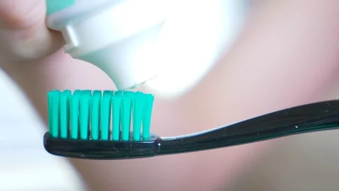 Squeezing toothpaste from a tube onto a toothbrush. Macro, close-up 4k. slow Stock Footage 83847849