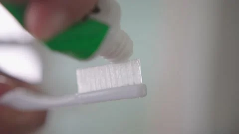 Squeezing white toothpaste from a tube onto toothbrush. Brushing her teeth Stock Footage 234688288
