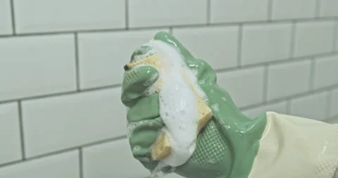Squeezing a yellow foam release sponge in your hand with a rubber cleaning glove Vidéo 230131654