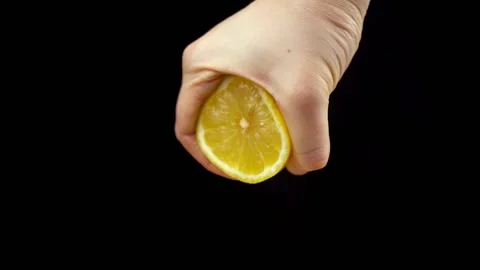 Squeezing yellow ripe lemon with hand on black background. Making lemon juice Stock Footage 134313496