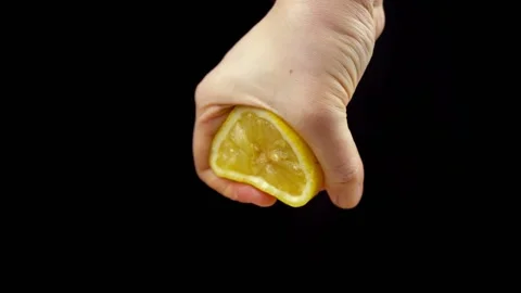 Squeezing yellow ripe lemon with hand on black background. Making lemon juice Stock Footage 134313563