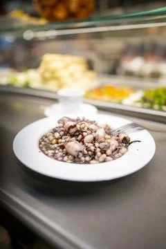 Squid and beans served in white bowl on counter at restaurant Stock Photos