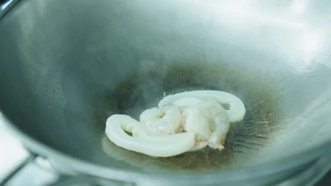 Squid and octopus are fried in oil in a deep metal pan. Stock Footage 331865745