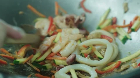 Squid and octopus are fried in oil in a deep metal pan. Cooking seafood Stock Footage 331866004