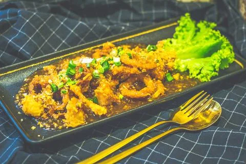 Squid breaded then deep fried then coated in garlic sauce Stock Photos