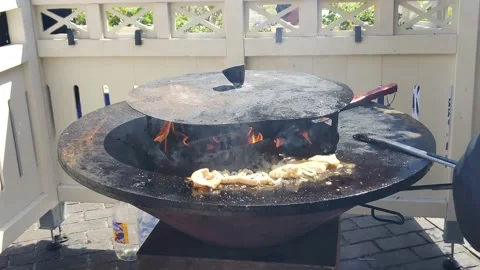 Squid is cooked on a round cast-iron outdoor grill with a fire in the middle Stock Footage 197373966