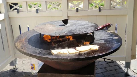 Squid is cooked on a round cast-iron outdoor grill with a fire in the middle Vidéo 200400224
