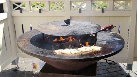 Squid is cooked on round cast-iron outdoor grill with fire in the middle Stock Footage 201472305