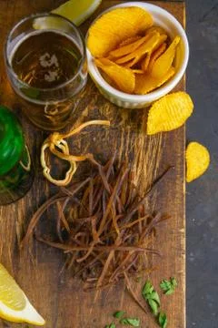 Squid dark cobweb with beer, lemon and potato chips on dark wooden board. Sna Stock Photos