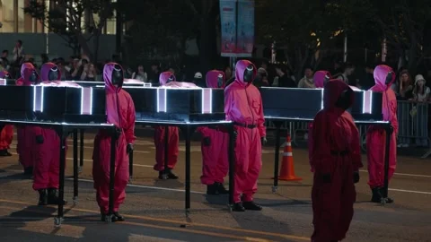 Squid Game Parade Guards with Glowing Ribbon-Wrapped Coffins in Seoul Stock Footage 312741290