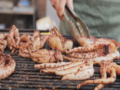 Squid, octopus, cuttlefish preparing on grill, close up. Video stock 74680554