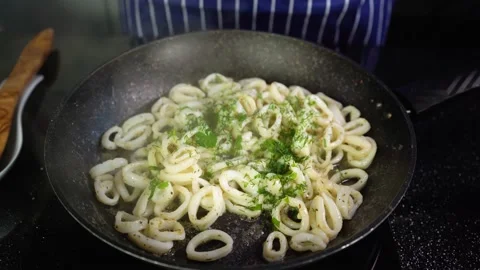 Squid rings are fried in a pan, the chef sprinkles the calamari rings with herbs Stock Footage 145661673