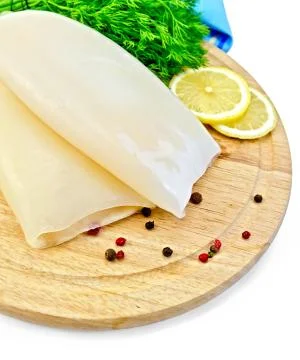 Squids with lemon and dill on a round board Stock Photos