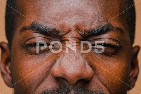 The squint of Afro American stylish man at brown studio wall Stock Photos