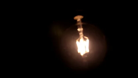 Squirrel cage filament light bulb, retro glowing bright lamp swinging  Stock Footage 89194566