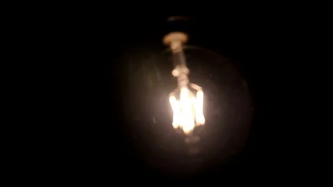 Squirrel cage filament light bulb, retro glowing bright trendy lamp swinging  Stock Footage 89194708